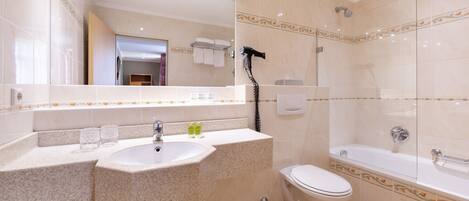 A modern bathroom with a granite countertop sink, a toilet, and a glass-enclosed shower.