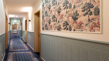 Un pasillo con alfombra estampada, paneles decorativos en la pared y un mural grande.