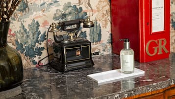 A vintage telephone, a red suggestion box, and a bottle of hand cleanser on a marble countertop.