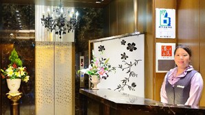 Zona de recepción con suelo de mármol, mostrador de recepción, candelabro y cámara de seguridad instalada en la pared.