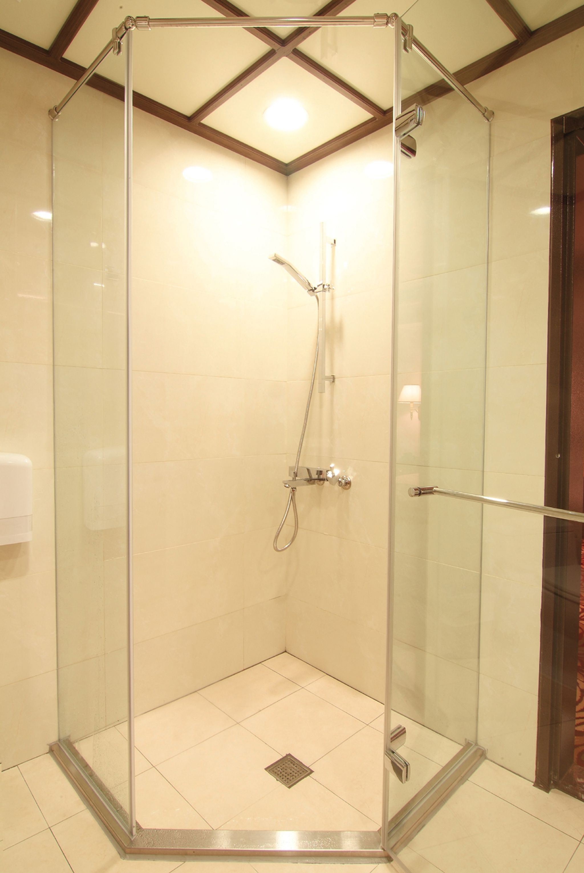 Eine separate Duschkabine mit Glaswänden, einer Handbrause und einem am Wand montierten Wasserhahn.