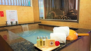 Un área de spa con un jacuzzi, una toalla y botellas de productos de baño.