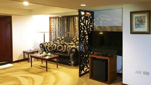 Una sala de estar con sofá, mesa de centro, televisor y un panel decorativo.