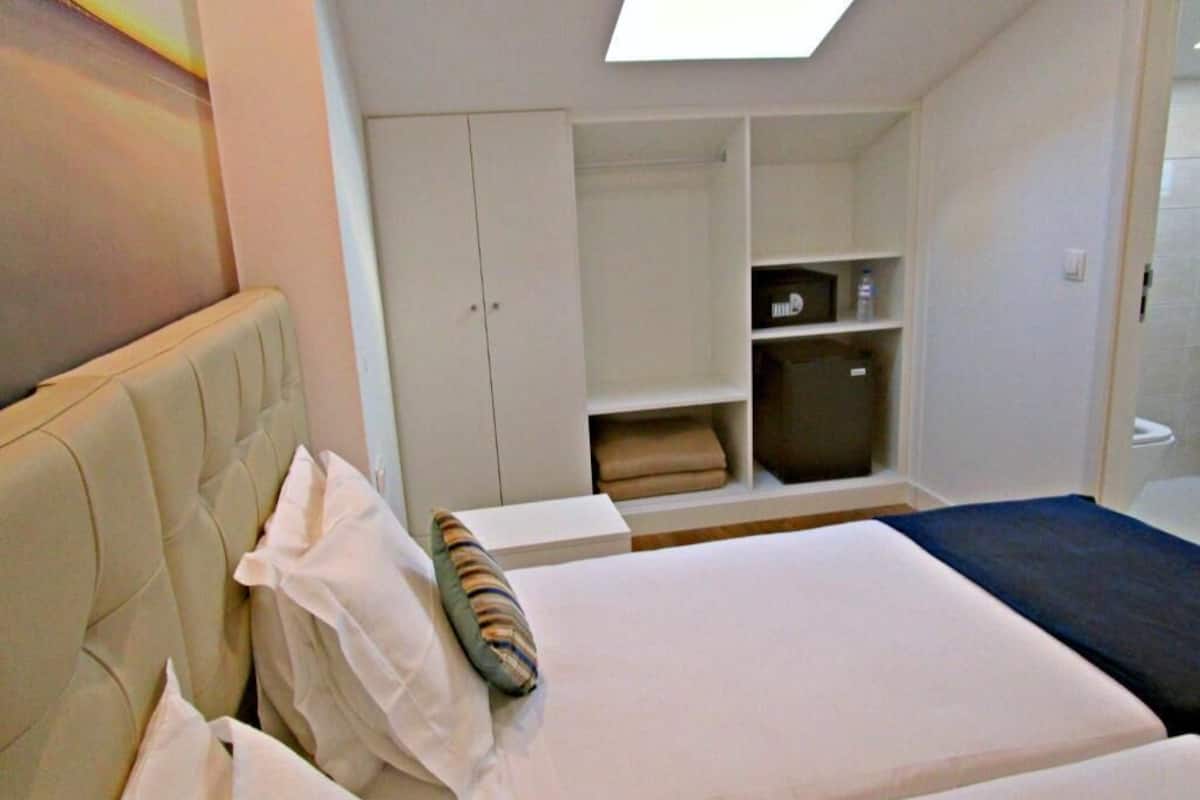 A bedroom with two beds, a wardrobe, and a small seating area.
