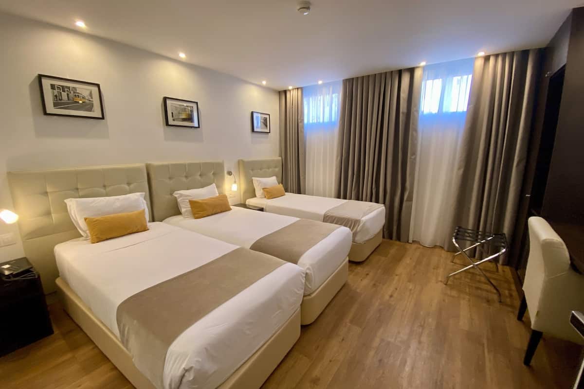 A hotel room with two beds, a chair, and a desk.