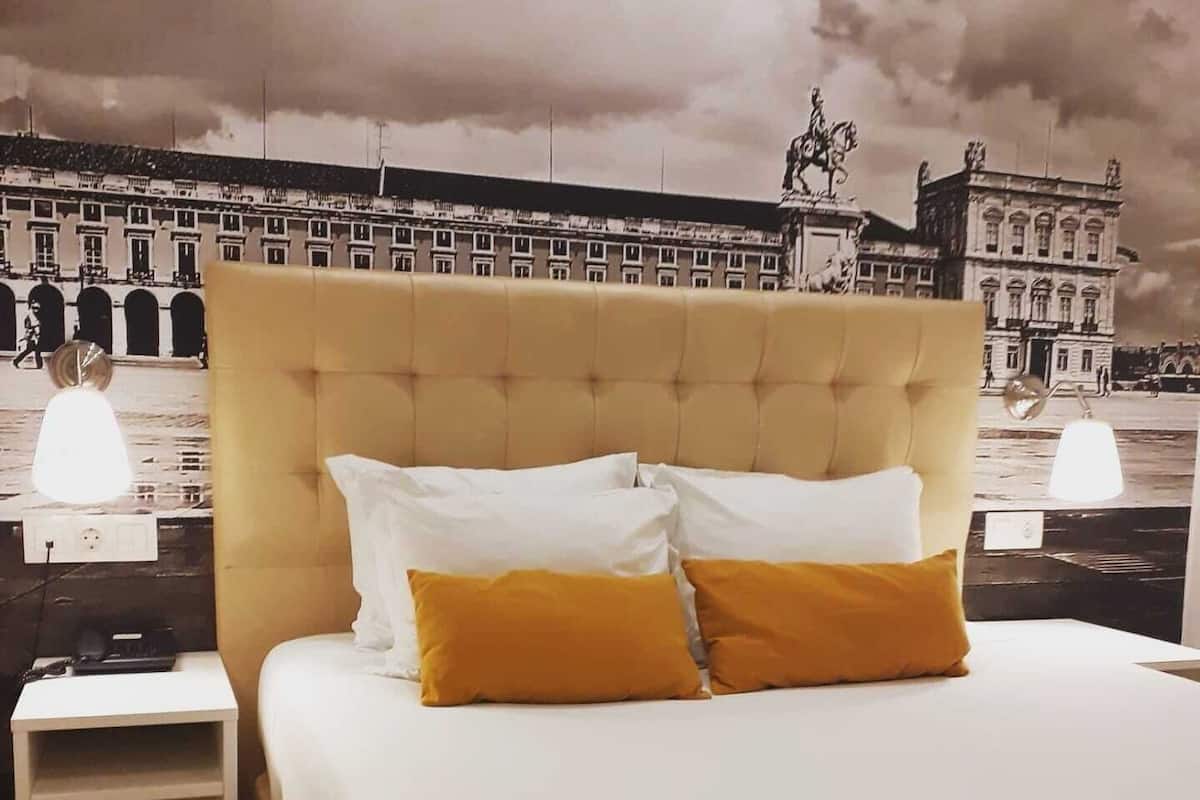 A hotel room with a large bed, a headboard, and a nightstand.