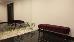 A modern lobby with a marble floor, a bench, and a row of purple flowers.