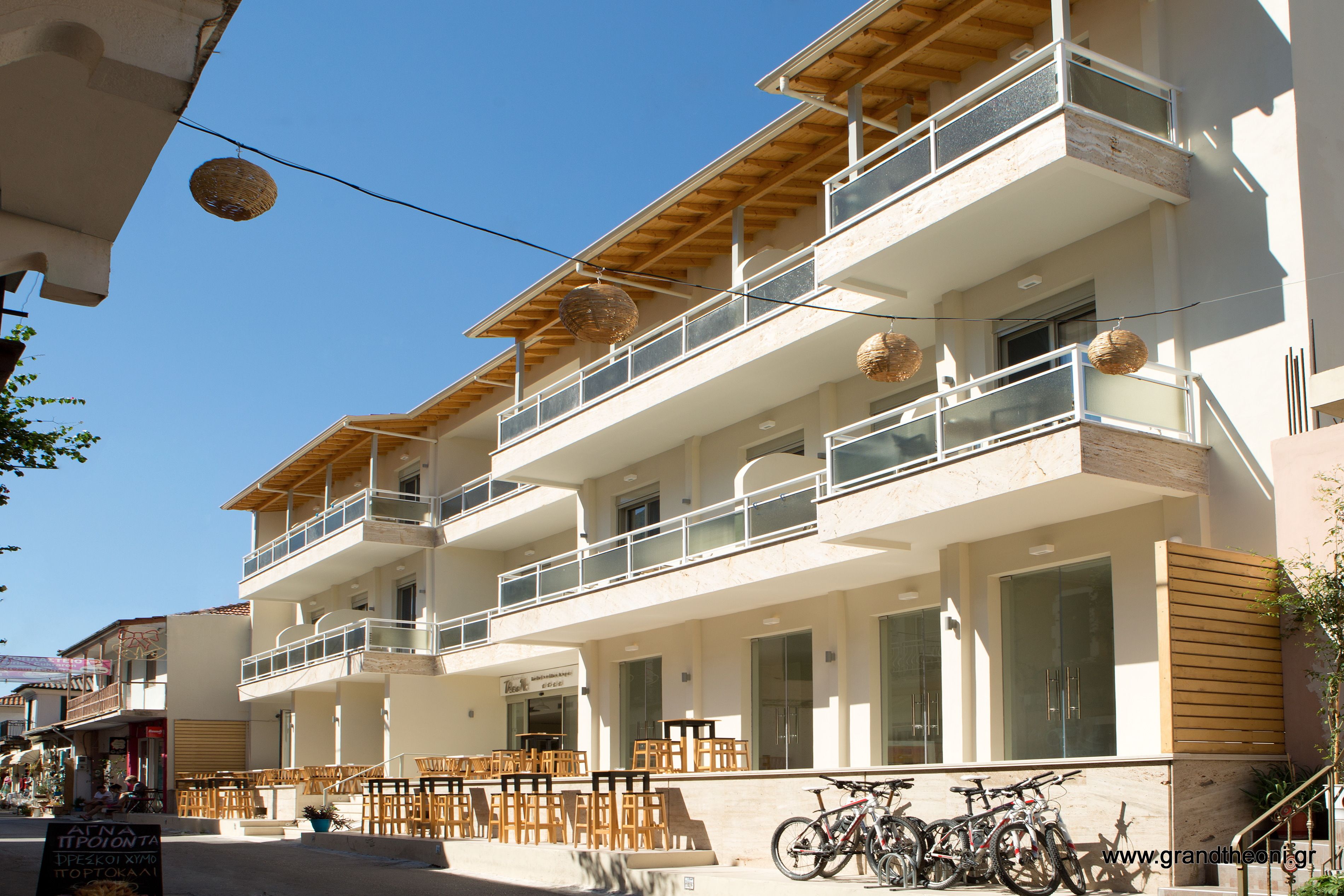 A multi-story building with balconies, outdoor seating, and bicycles parked outside.