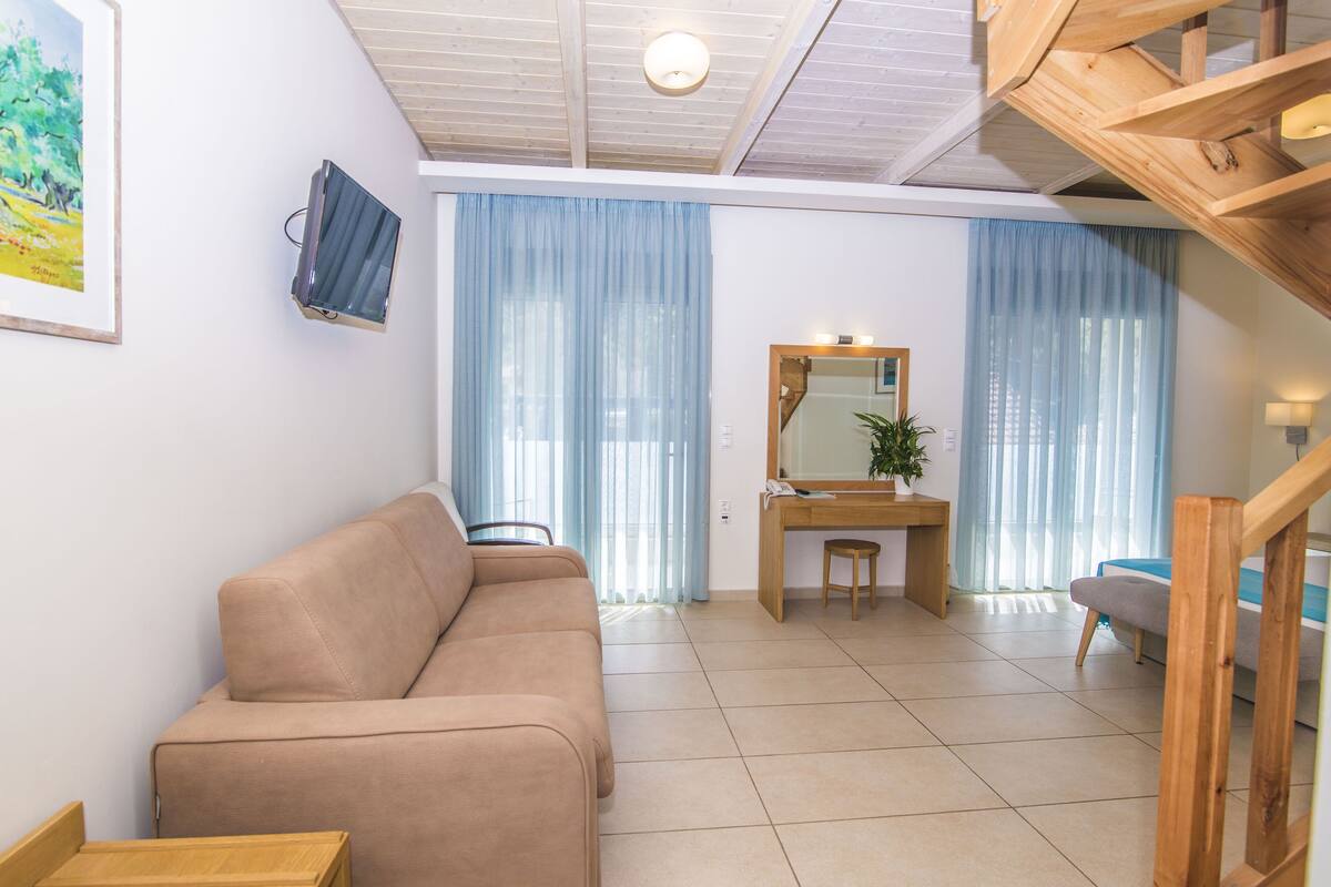 Un salon avec un canapé beige, un bureau en bois et un escalier.