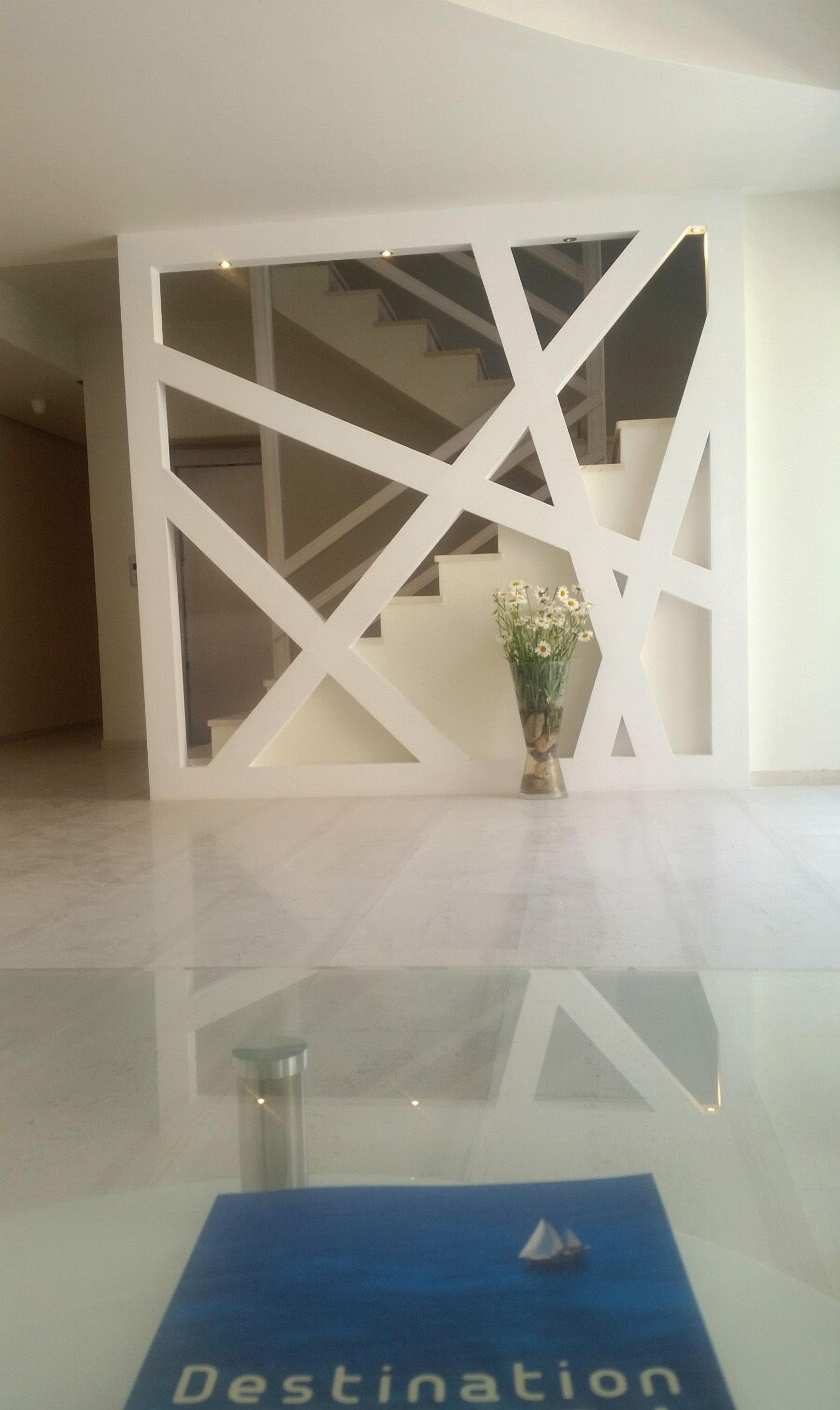 A modern lobby with a geometric white wall design, a glass reception desk, and a blue sign with the word "Destination".