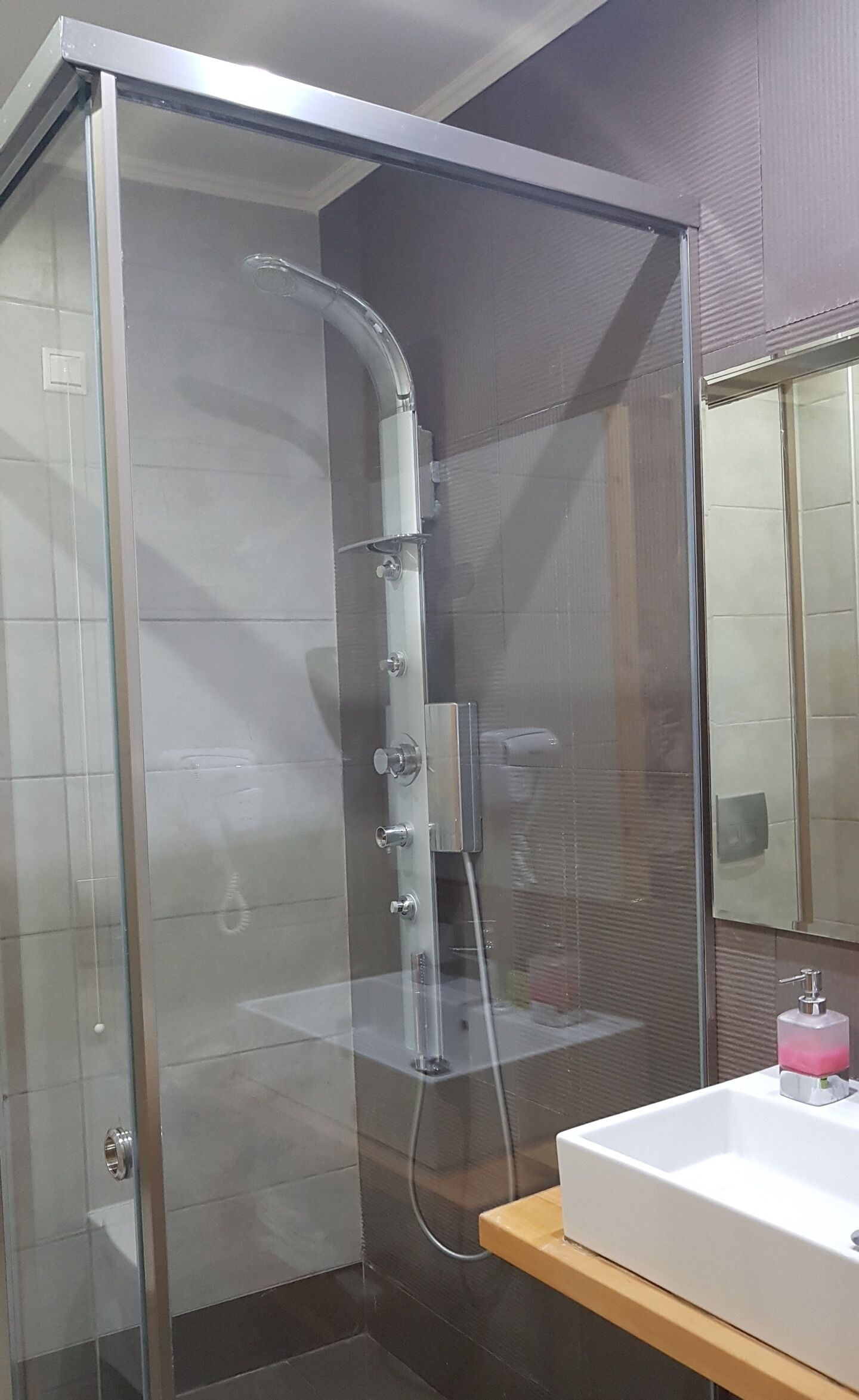 Une salle de bain moderne avec une douche à parois de verre, un lavabo blanc et un miroir.