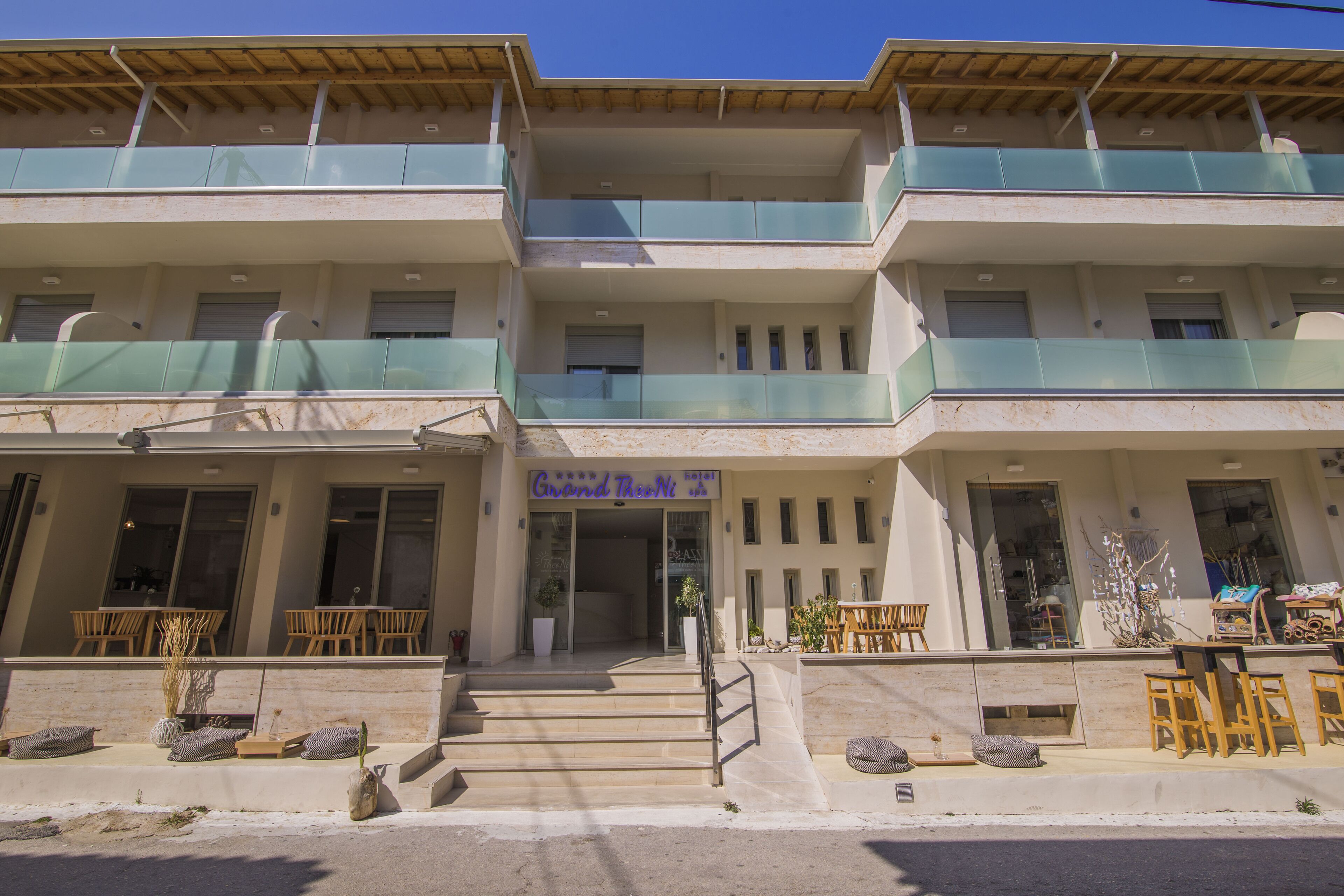 A two-story building with a balcony on the ground floor and a sign reading "Grand Theoni".