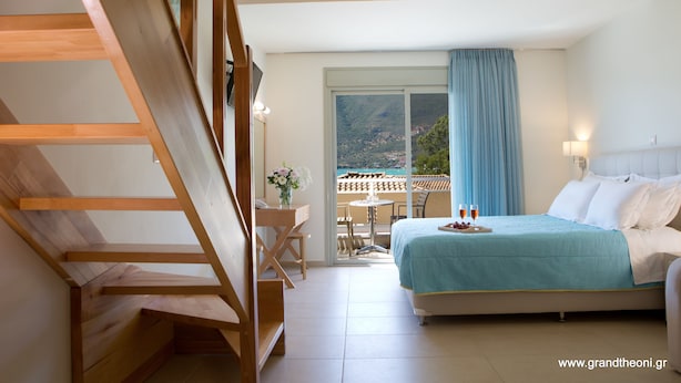 Une chambre avec un lit, un bureau et une chaise. Il y a un balcon avec une table et des chaises.