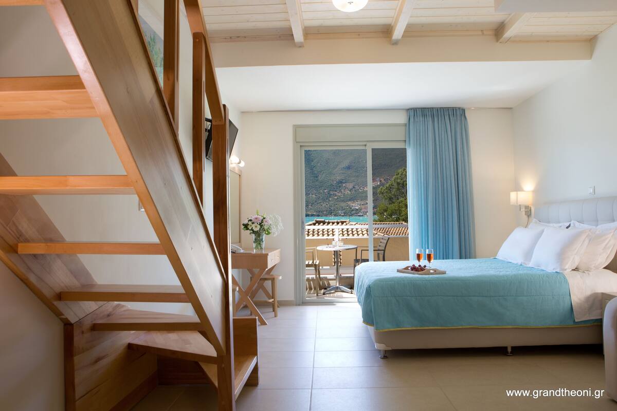 Une chambre avec un lit, un bureau et une chaise. Il y a un balcon avec une table et des chaises.