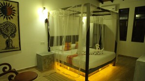Una cama con dosel y cuatro postes, con una luz nocturna, un banco de madera y una obra de arte colgada en la pared.