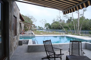 A pool area with two chairs and a covered patio.