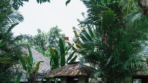Um resort tropical com uma cabana de telhado de palha, vegetação exuberante e um gramado bem cuidado.