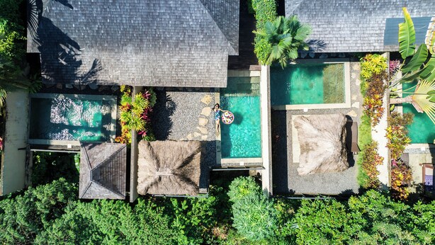 Uma área de piscina no terraço com várias piscinas, rodeada por vegetação exuberante e plantas tropicais.