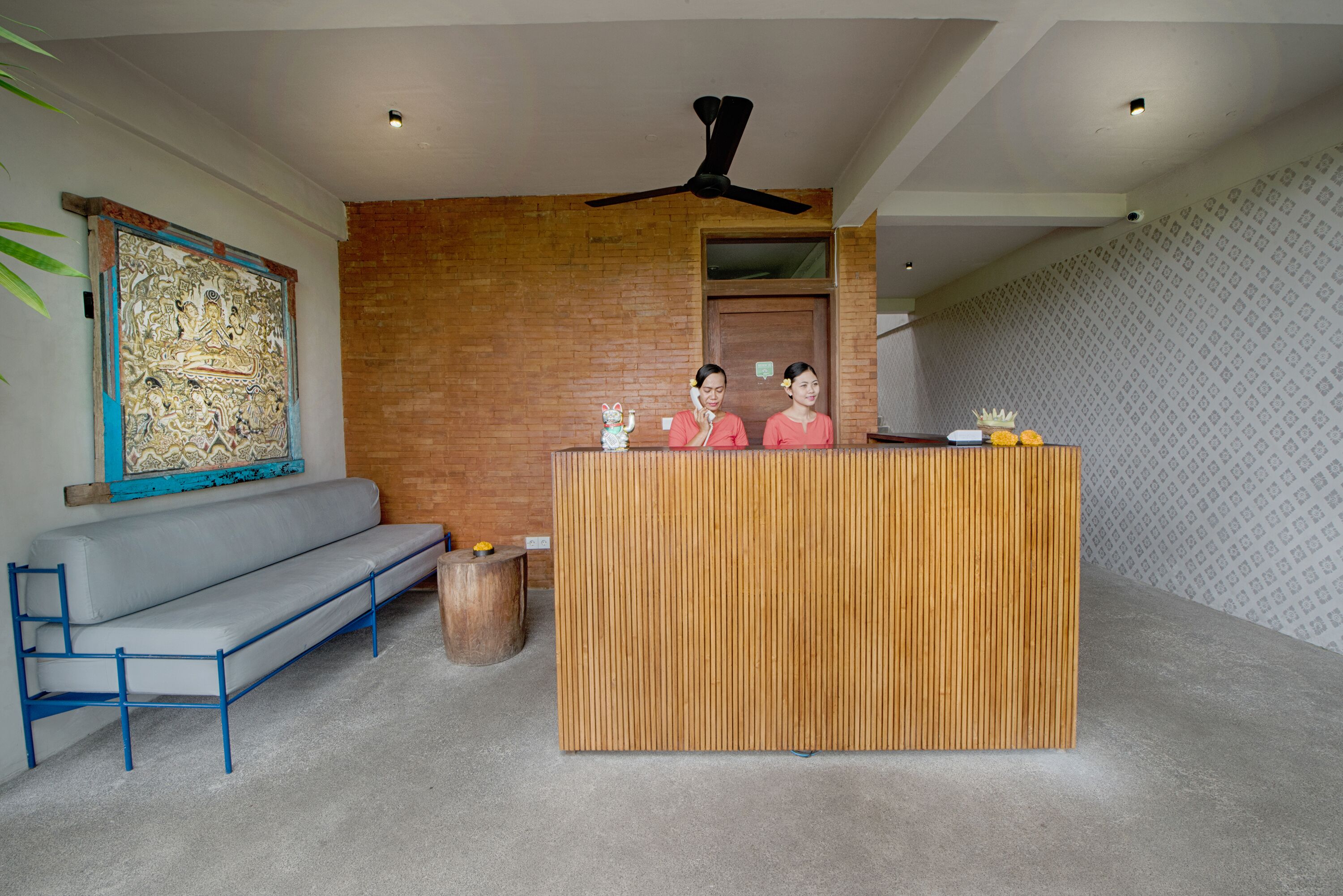 A reception area with a wooden reception desk, a grey sofa, and a large abstract painting on the wall.