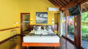 A bedroom with a bed, a wooden ceiling, a wall-mounted TV, and a large window with a view of greenery. - Temuku Ubud Villas (Ubud)