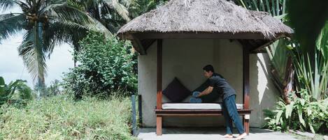 A thatched-roof hut with a bench and a pool.