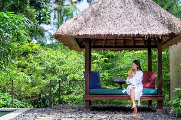 A thatched-roof gazebo with a bench, surrounded by lush greenery. - Temuku Ubud Villas (Ubud)
