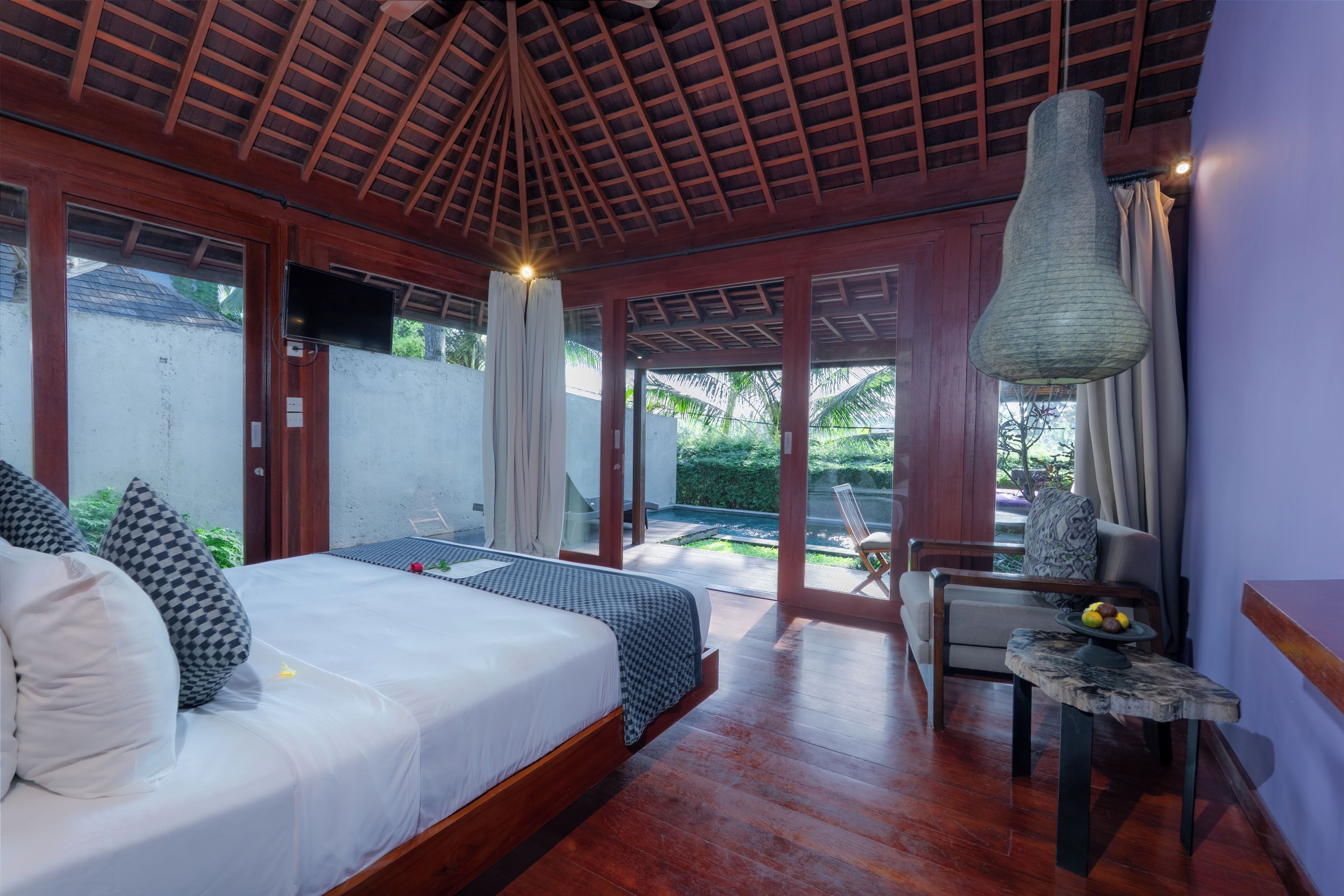 Un dormitorio con cama, escritorio con lámpara y vistas al exterior.