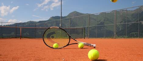 A tennis court with a net, tennis balls, and a racket.