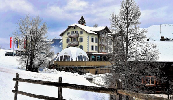 A hotel with a snow-covered roof, a large dome structure, and multiple windows. - The Alpina Mountain Resort  (Tschiertschen)
