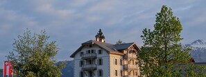 A multi-story building with balconies, surrounded by trees and mountains in the background. - The Alpina Mountain Resort  (Tschiertschen)