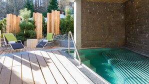 A spa area with a hot tub, wooden deck, and lounge chairs. - The Alpina Mountain Resort  (Tschiertschen)