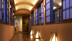 A hallway with wooden flooring, large windows with traditional design, and wall-mounted lighting fixtures. - Satoyama no Kyujitsu Kyoto Keburikawa (Kameoka)