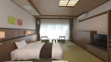 A hotel room with two beds, a TV, a small table, and two chairs.