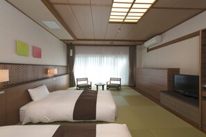 Habitación de hotel con dos camas, un televisor, una mesita y dos sillas.