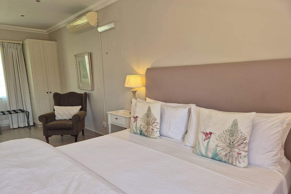 Ein Hotelzimmer mit einem großen Bett, einem Sessel, einem Nachttisch mit Lampe und einem Kleiderschrank.