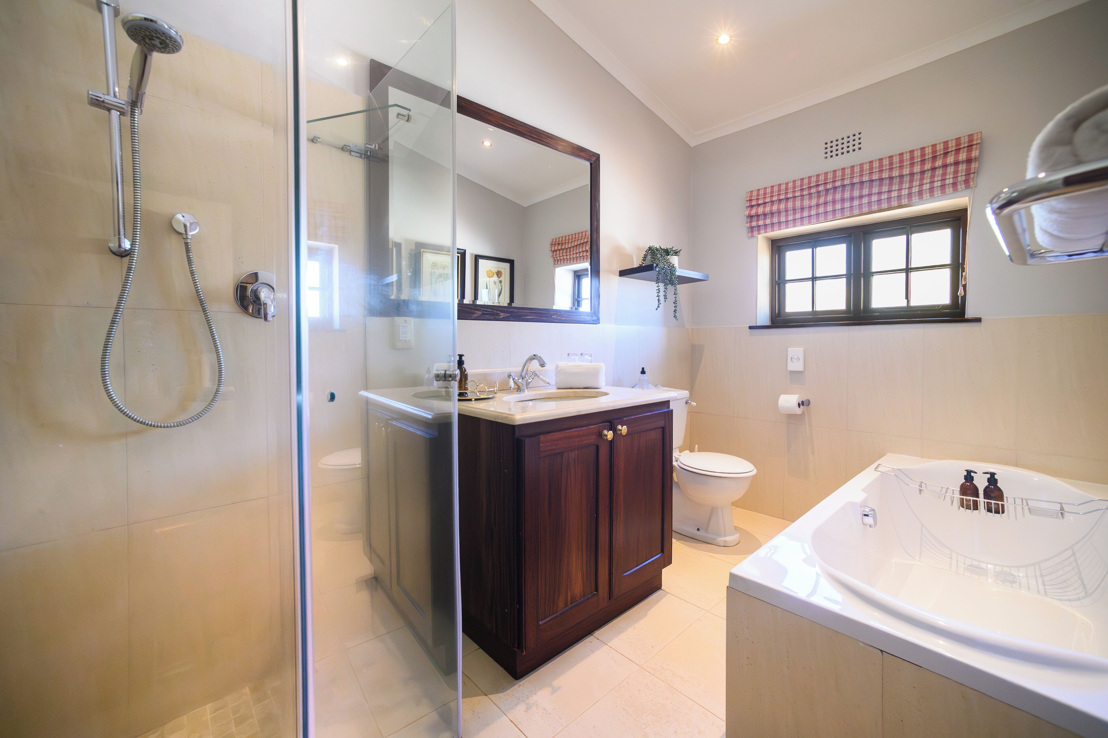 A bathroom with a glass shower enclosure, a vanity with a mirror, a toilet, and a bathtub.