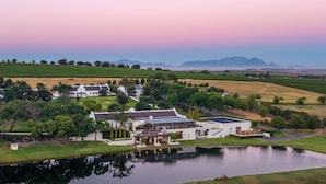 Een uitgestrekt landgoed met meerdere gebouwen, een meer en omliggende velden.