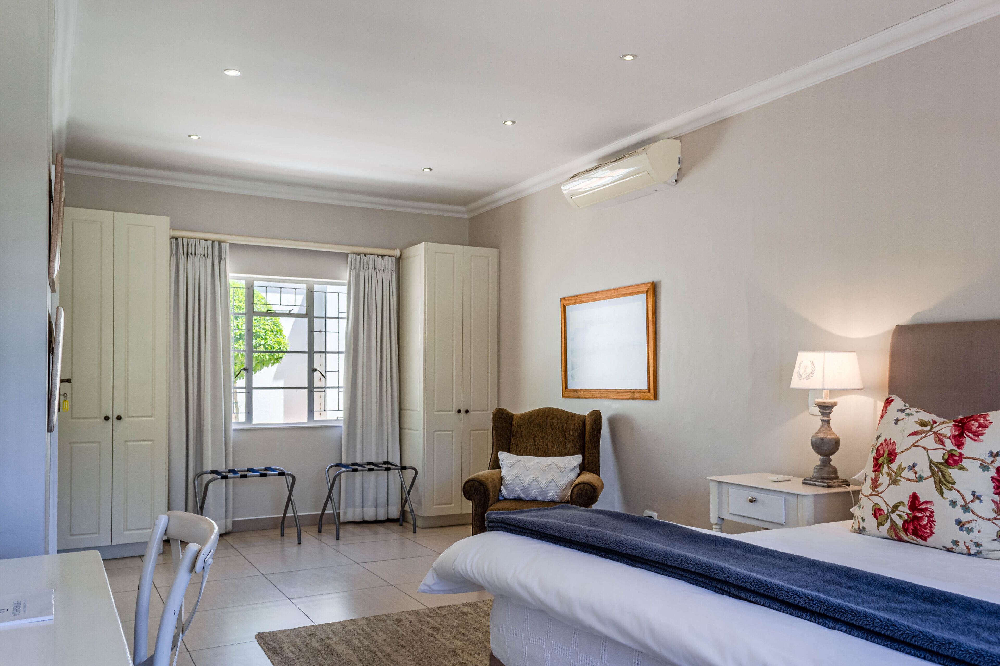 Une chambre à coucher avec un lit, une chaise, un bureau et une fenêtre avec des rideaux.