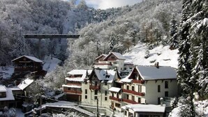 A snow-covered mountain village with chalet-style buildings, a ski lift, and a bridge.