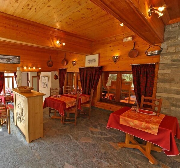 Een gezellig houten interieur met gedekte tafels, stenen muren en een rustieke sfeer.