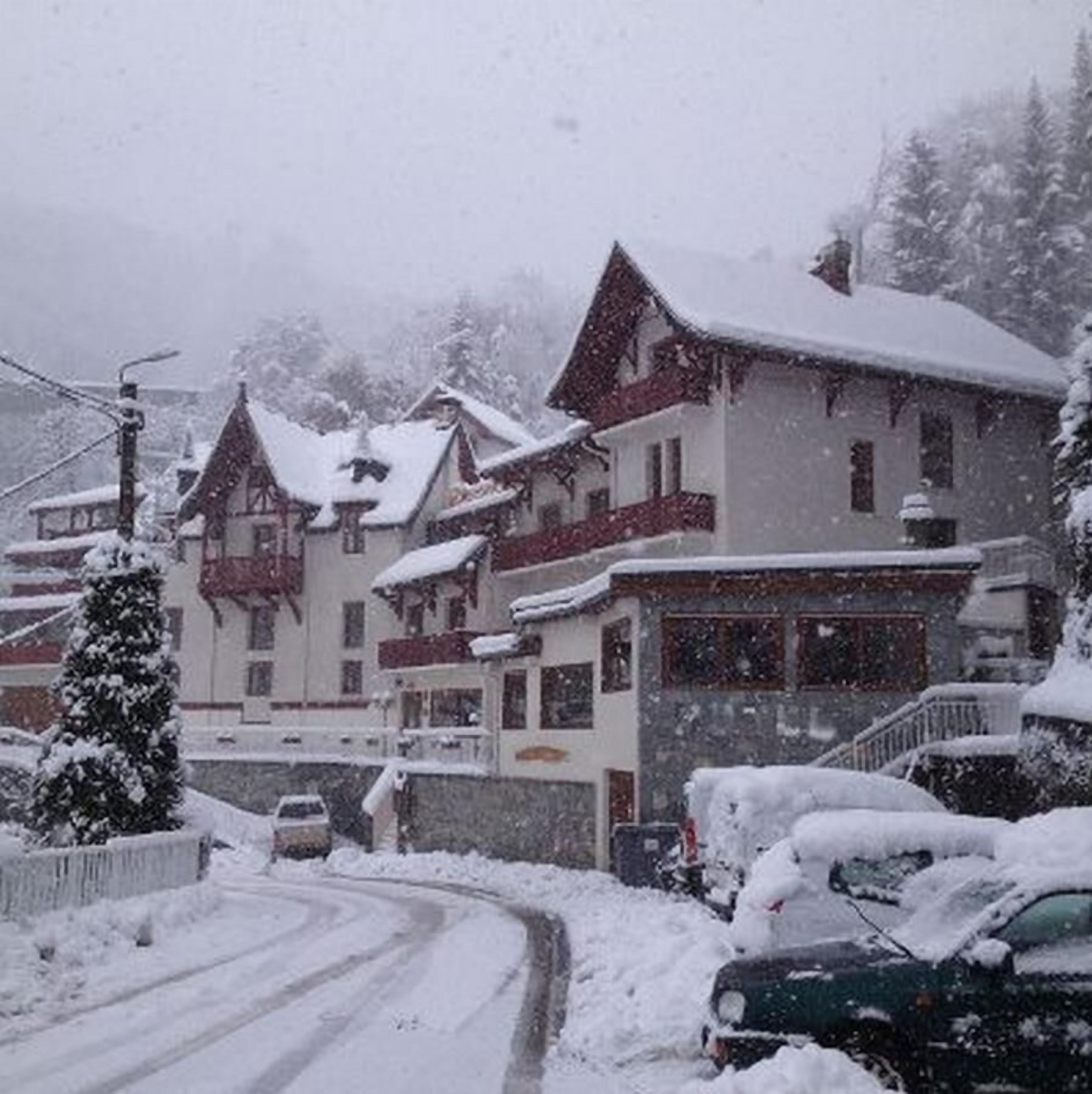 Un edificio cubierto de nieve con varios pisos, una escalera visible y un coche estacionado adelante.