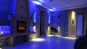 A room with a stone fireplace, a bench with towels, and a black chair.