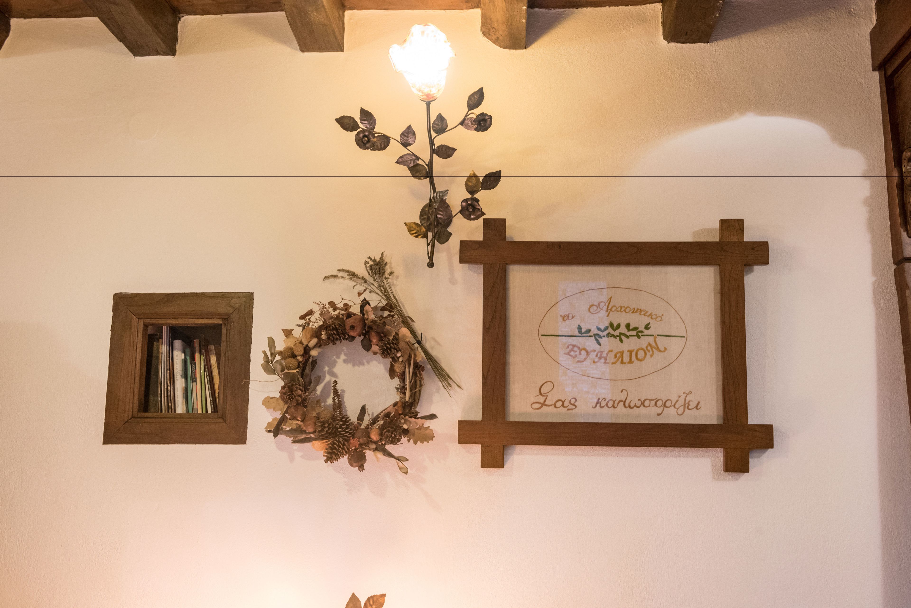 Una pared con un cuadro enmarcado, un adorno festivo y una lámpara de pared.