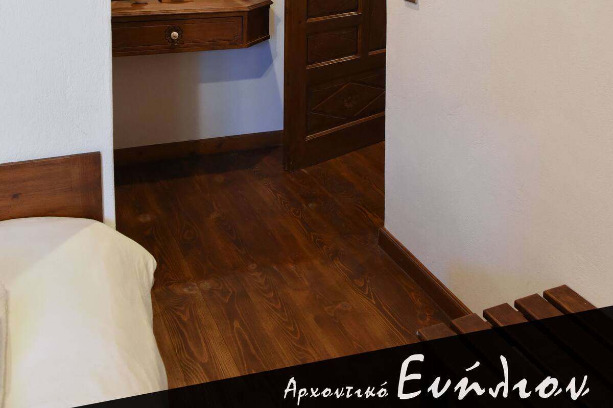 Un pasillo estrecho con suelo de madera, una puerta de madera y un espejo en la pared.