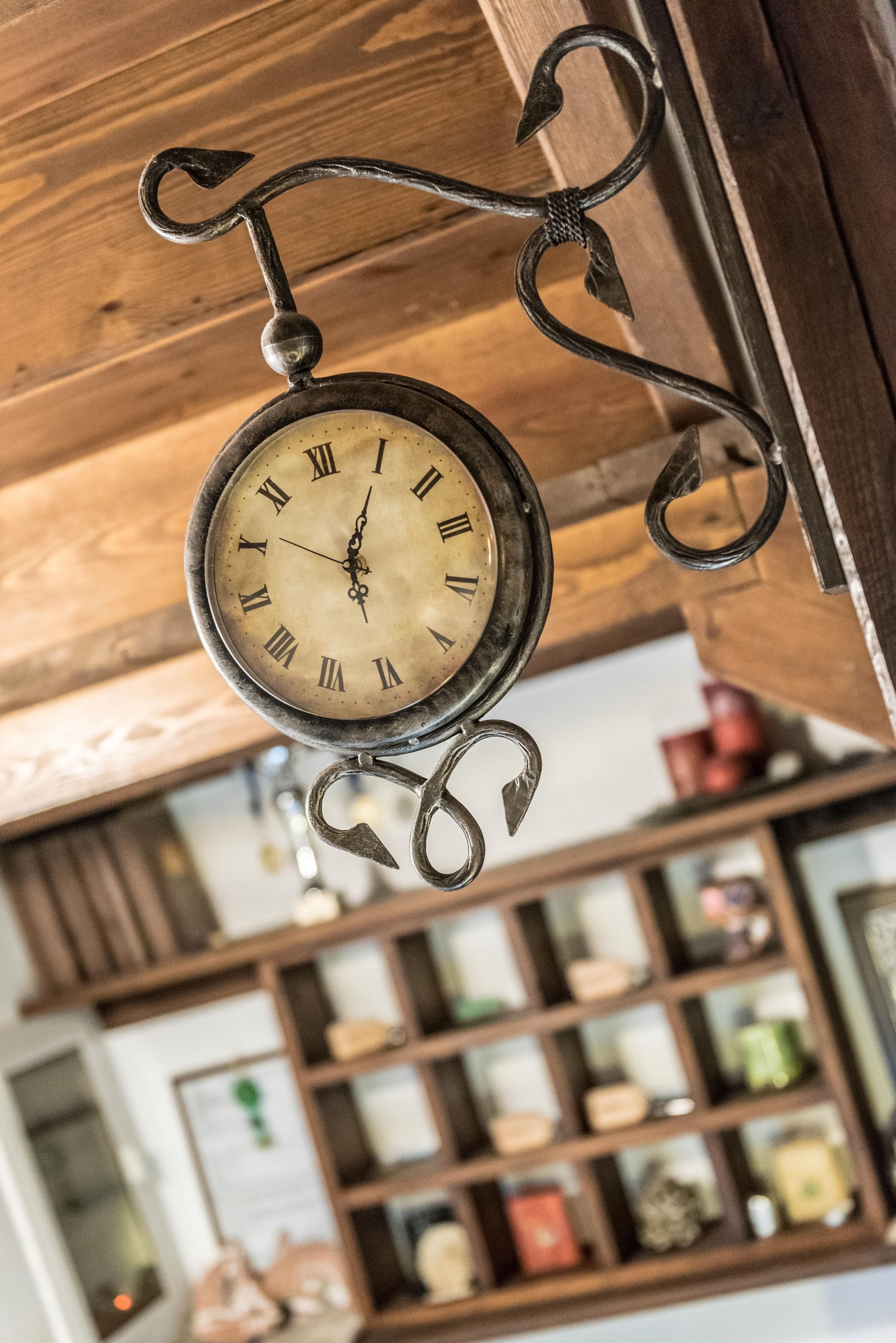 Un orologio d'epoca con numeri romani appeso al soffitto in legno.