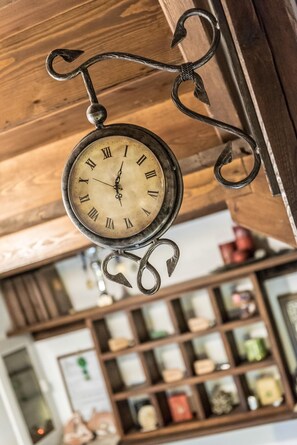 A vintage clock with Roman numerals hanging from a wooden ceiling. - Archontiko Evilion (Volos)