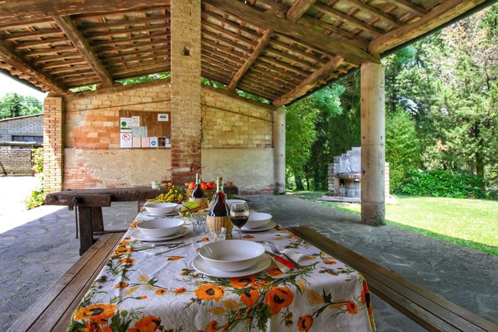 Een buiten eethoek met een tafel gedekt voor vier personen, omgeven door een houten pergola.