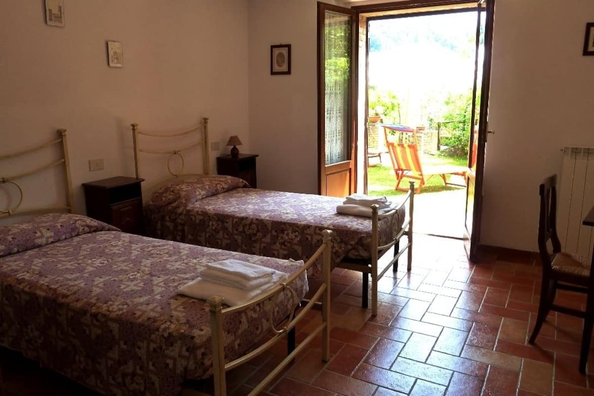 Habitació amb dos llits, una cadira i una taula.