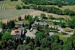 Luchtbeeld van een landgoed met meerdere gebouwen, een zwembad en omliggend groen.