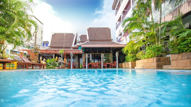 A swimming pool with a view of a building with a tiled roof and balconies. - Kelly’s Residency (Patong)